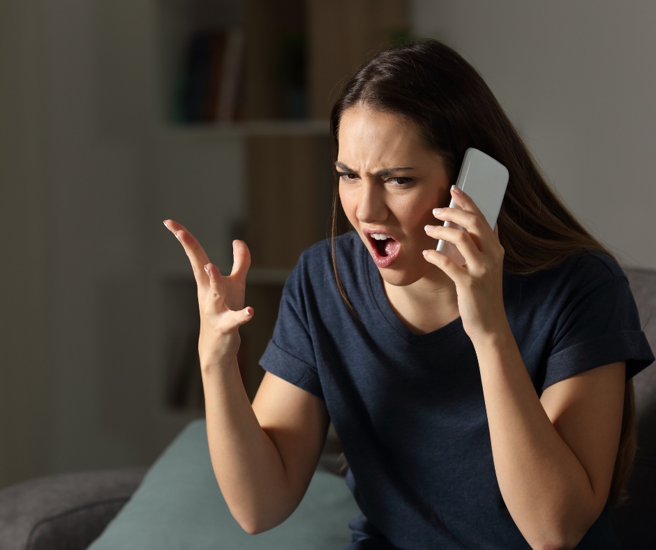 Người phụ nữ đang tức giận khi gọi điện thoại, minh họa cho tình trạng căng thẳng và nhu cầu massage giúp giảm cơn nóng giận
